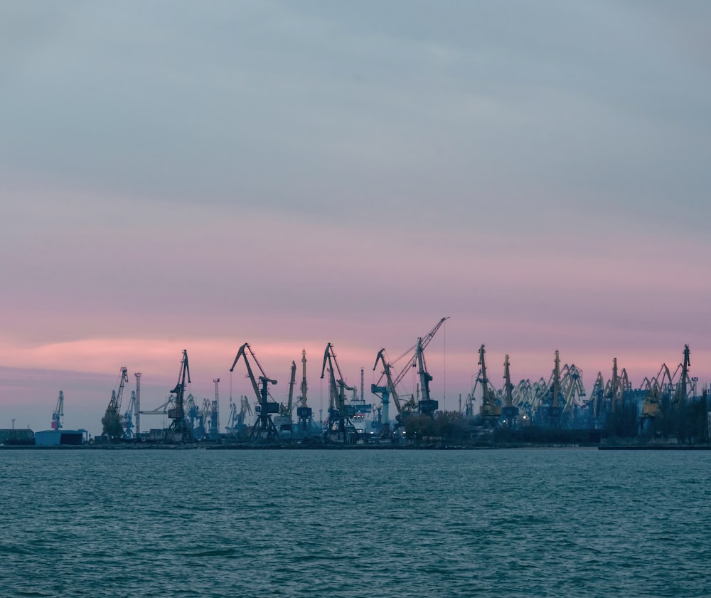 a harbor filled with lots of cranes under a cloudy sky