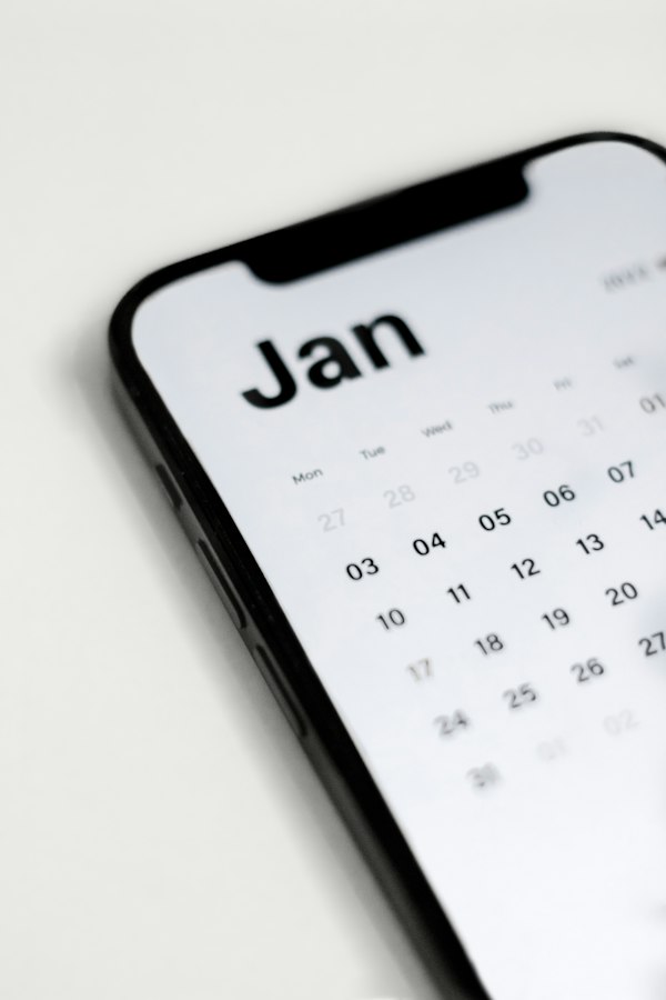 A smartphone lying on a gray surface with a calendar app open on the screen