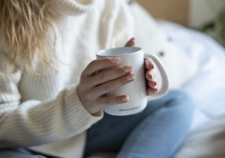 a woman sitting on a bed holding a coffee mug