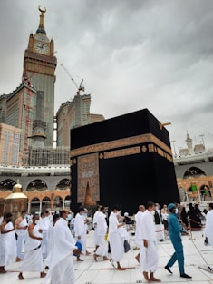 A serene image of pilgrims in white ihram clothing walking towards the Kaaba in Mecca, surrounded by the beautiful architecture of the mosque.