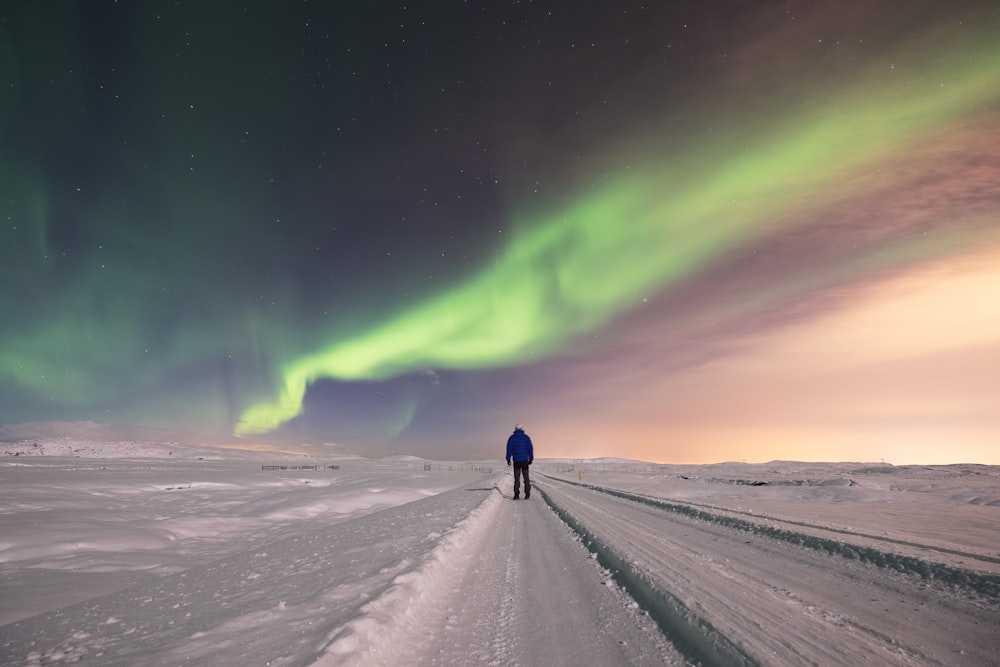 a person standing in the middle of a snow covered road