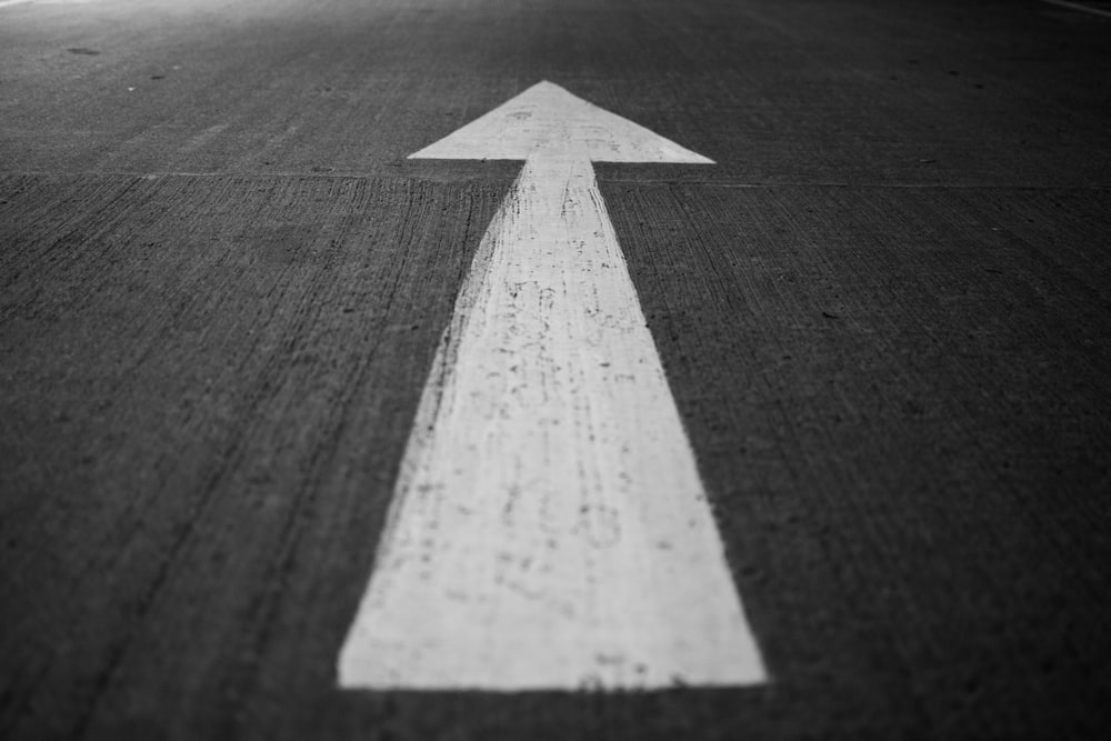 Una foto en blanco y negro de una flecha pintada en una carretera