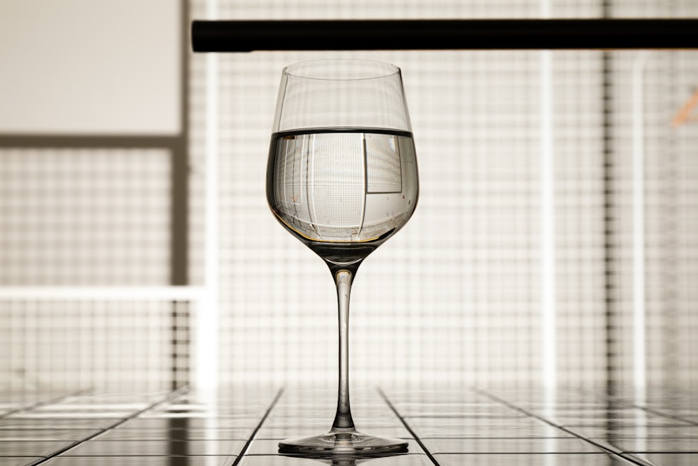 a glass of wine sitting on top of a tiled floor