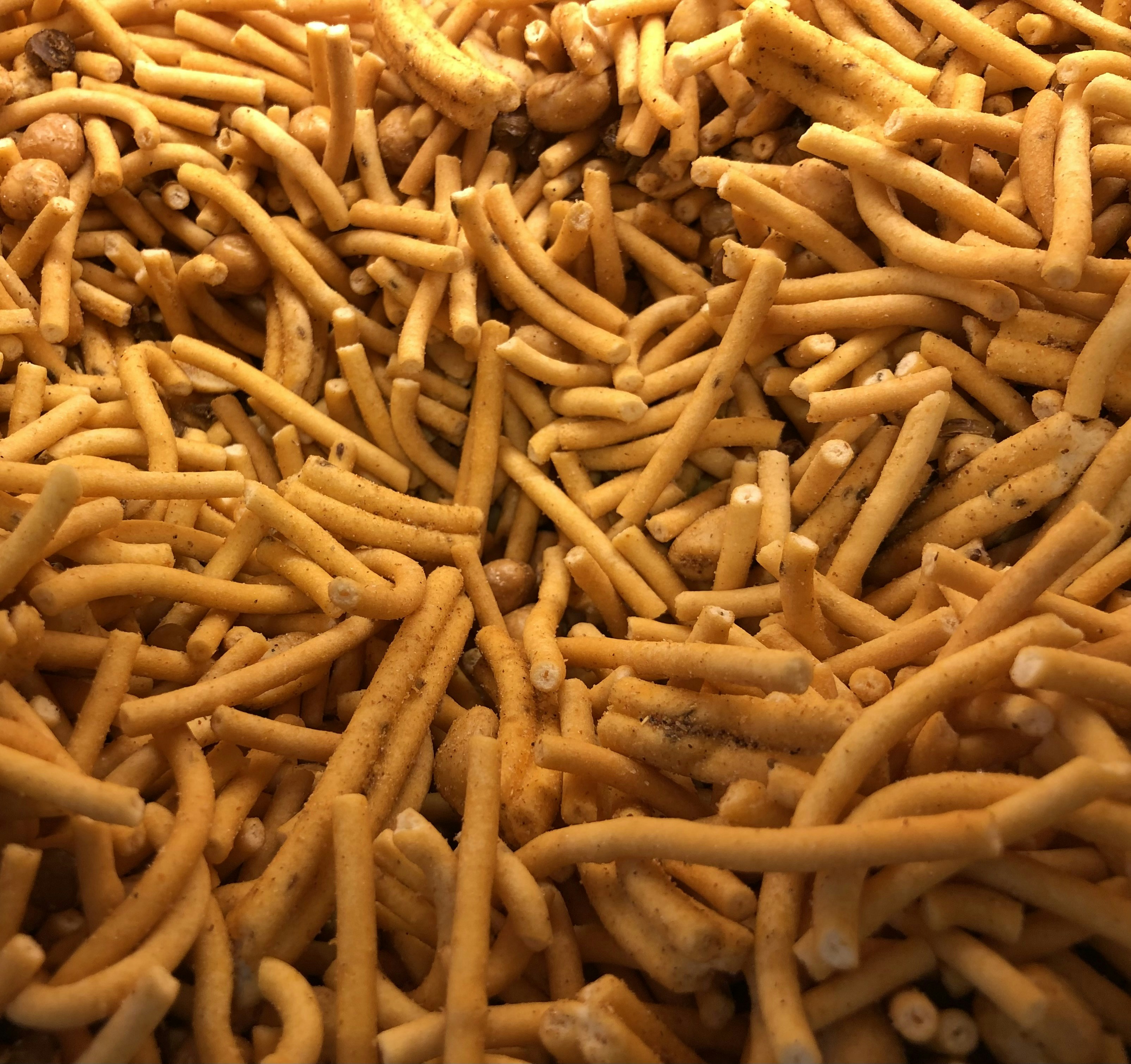 Close-up of golden besan chickpea flour texture being sifted through fine mesh screen, warm natural light