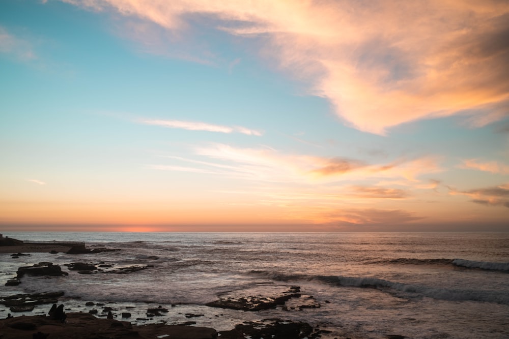 the sun is setting over the ocean on a cloudy day