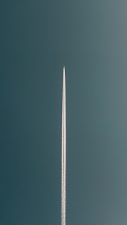 a plane flying in the air with a contrail in the sky