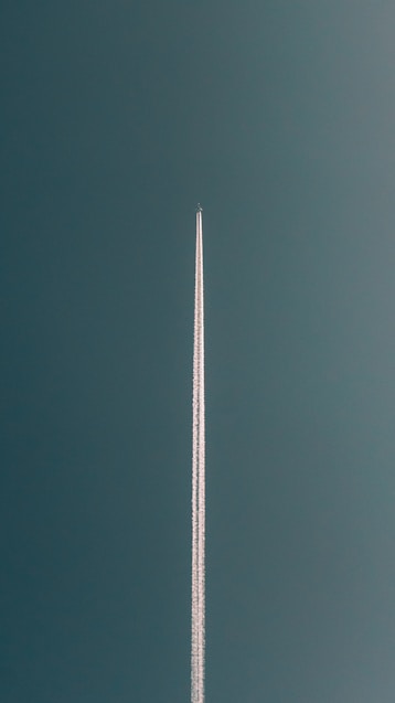 a plane flying in the air with a contrail in the sky