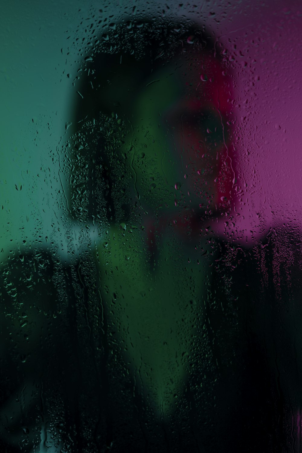 a woman standing in front of a window covered in rain