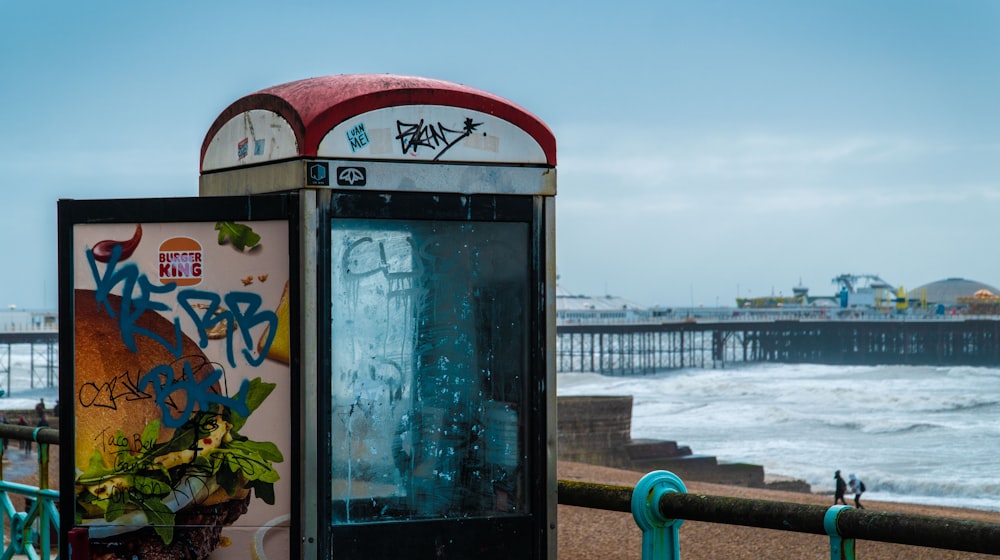 a bus stop next to the ocean with graffiti on it