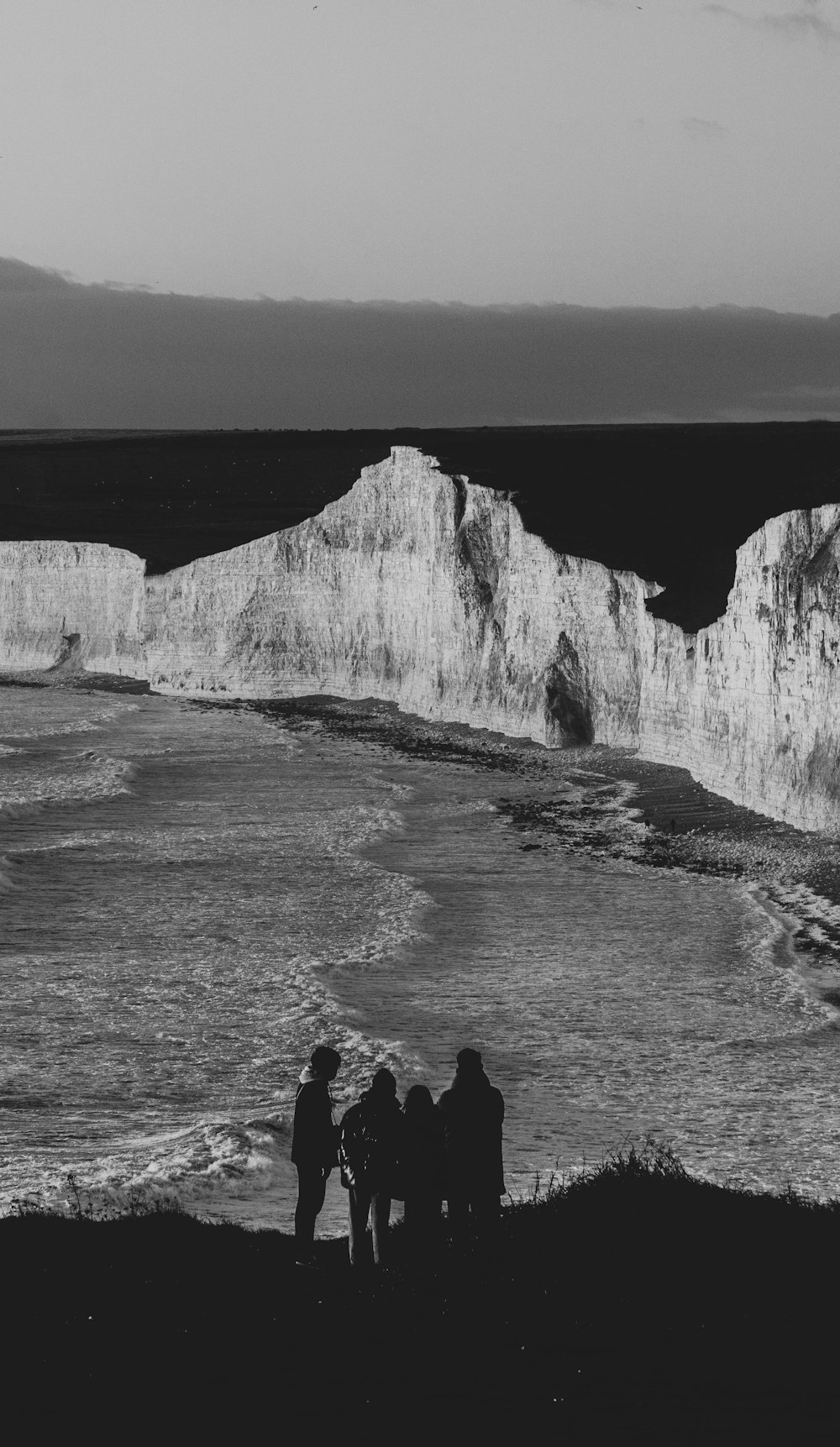 a group of people standing on top of a beach next to the ocean