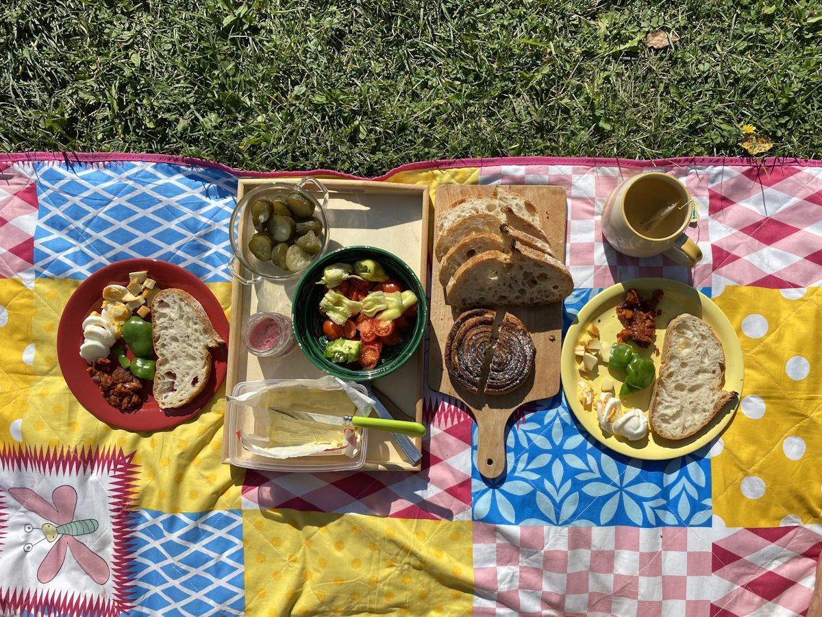 Outdoor picnic setup with pillows, tray service, and brunch items