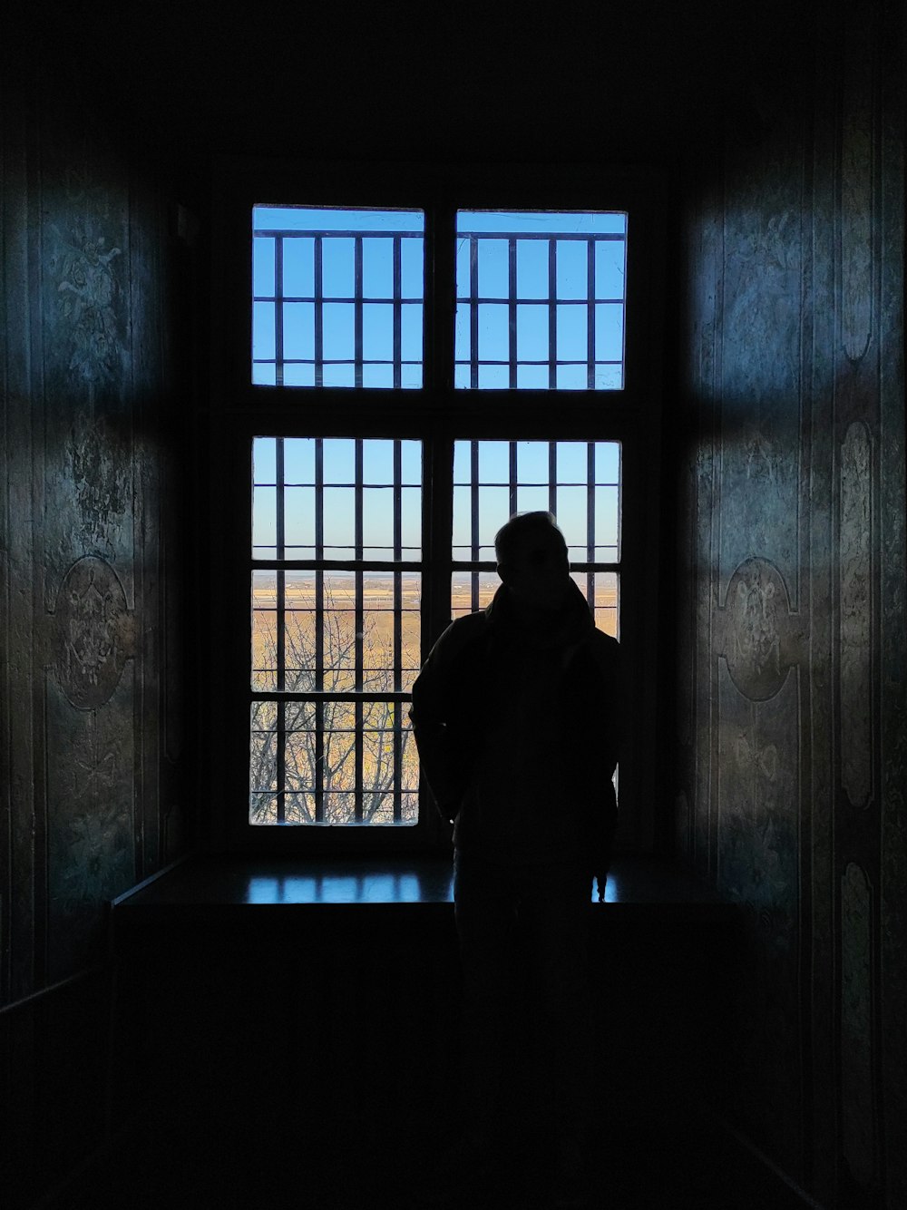 a person standing in front of a window in a dark room