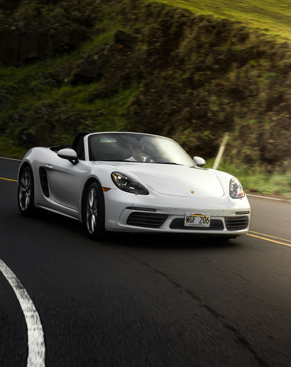 a white sports car driving down a road