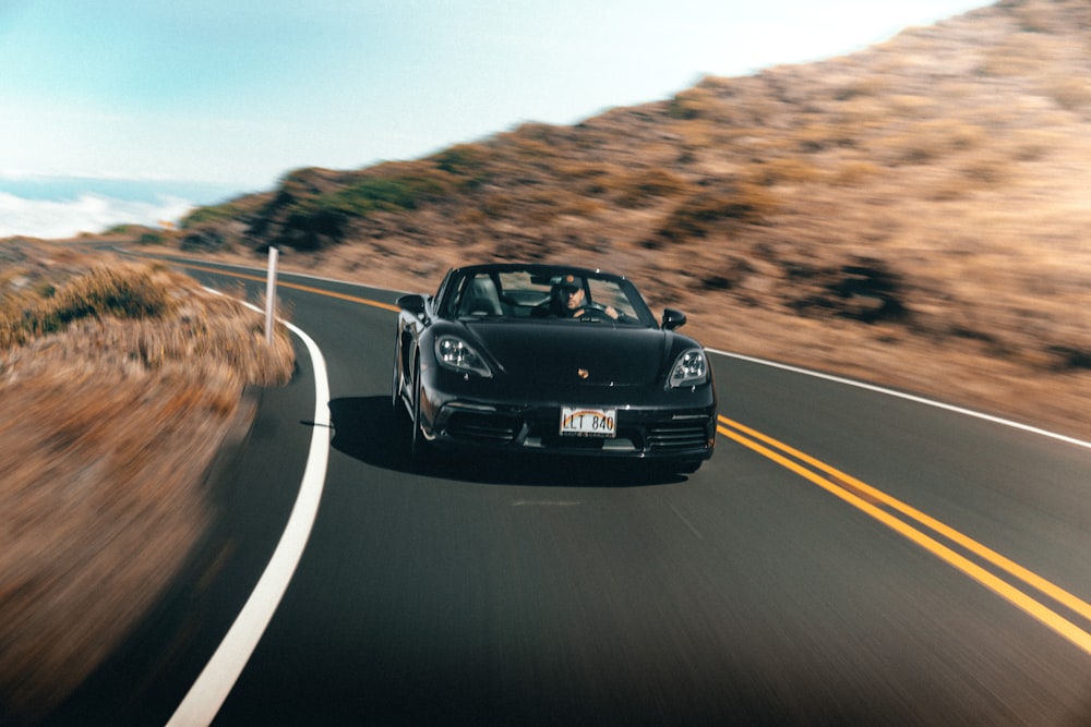 a black sports car driving down a mountain road