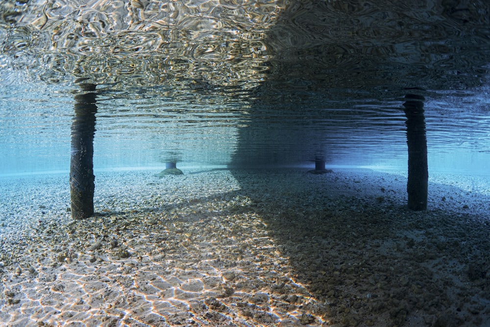 Eine Unterwasseransicht eines Sandstrandes mit zwei Stangen, die aus dem Wasser ragen