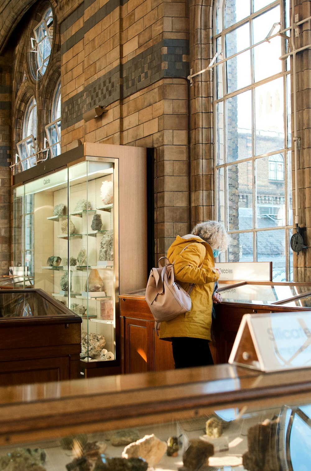 a woman is looking at a display case in a museum