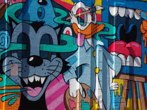 A vibrant hat with a bold rubber duck patch, set against a graffiti wall bursting with neon colors.