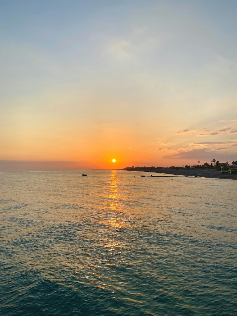 a sunset over the ocean with a boat in the water