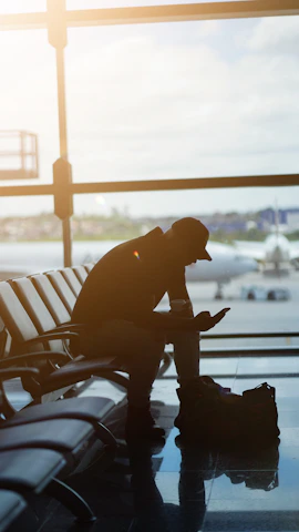 a man sitting at an airport looking at his cell phone