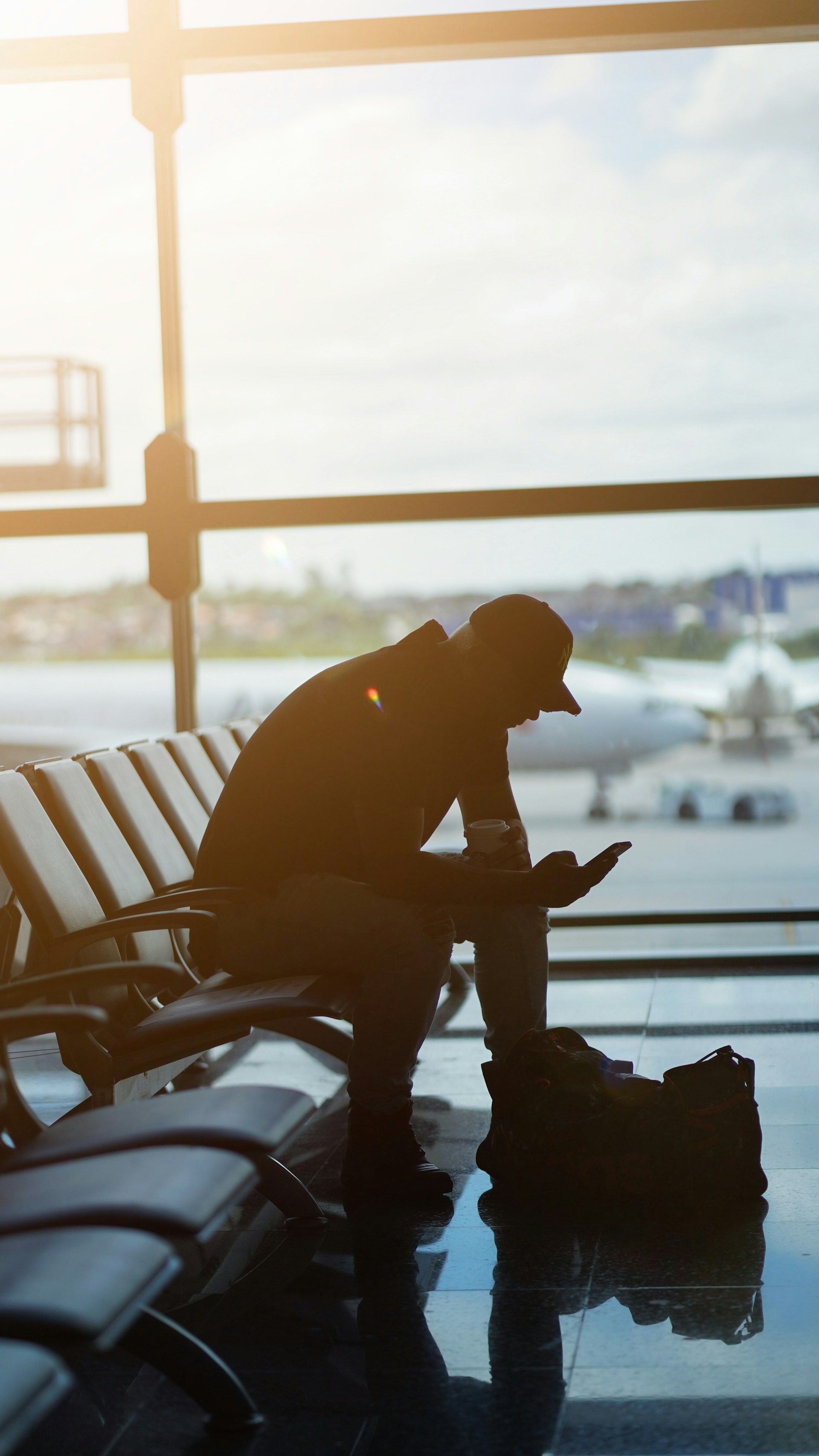 a man sitting at an airport looking at his cell phone