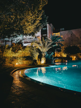 a large swimming pool surrounded by trees at night
