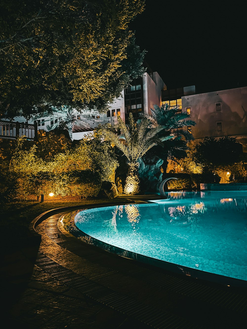 a large swimming pool surrounded by trees at night