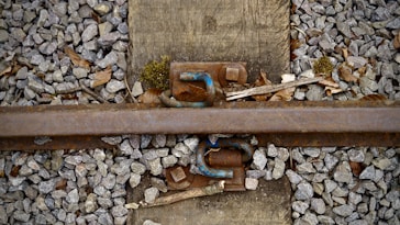 a rusted metal pipe laying on top of a pile of rocks