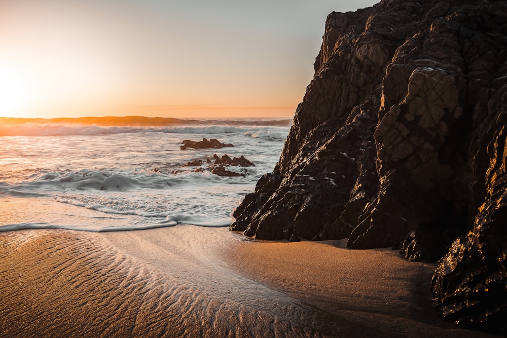 the sun is setting over a rocky beach