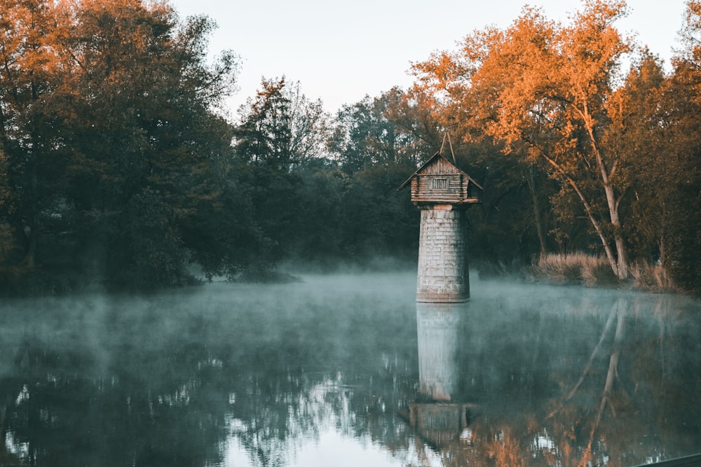 a small tower in the middle of a lake surrounded by trees