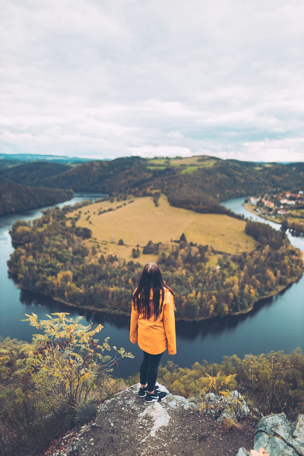 a woman standing on top of a hill overlooking a river