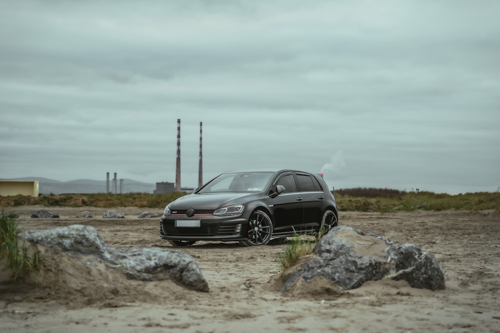 a black car is parked in the dirt