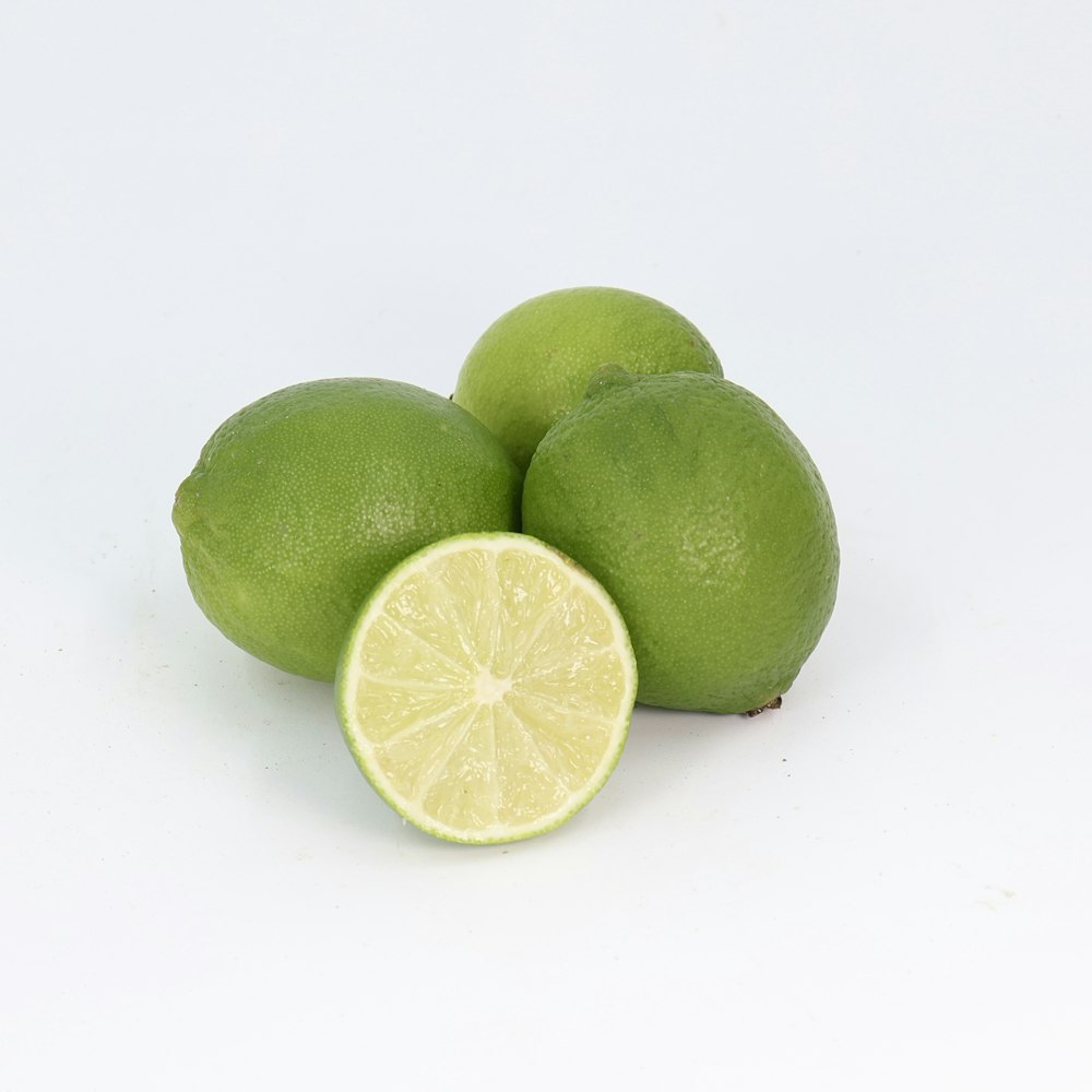 three limes with one cut in half on a white background
