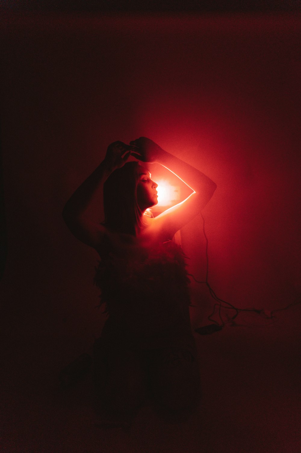 a woman standing in a dark room with a red light