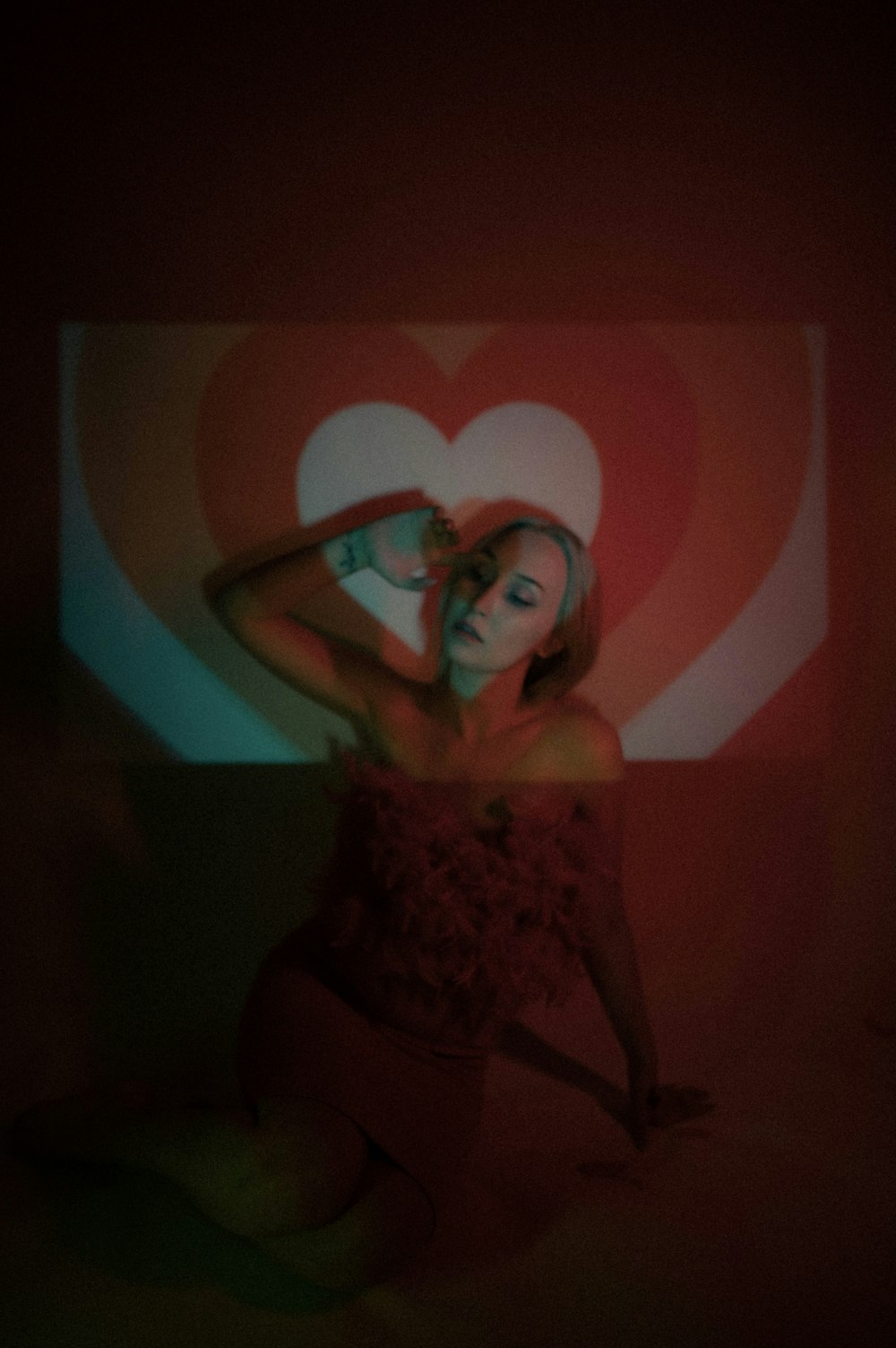 a woman in a red dress sitting in front of a heart