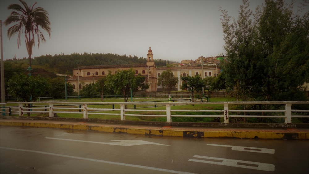 a road with a fence and a building in the background