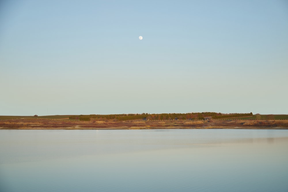 a large body of water sitting under a blue sky