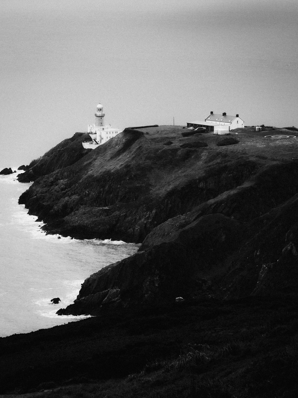 a black and white photo of a lighthouse on a hill