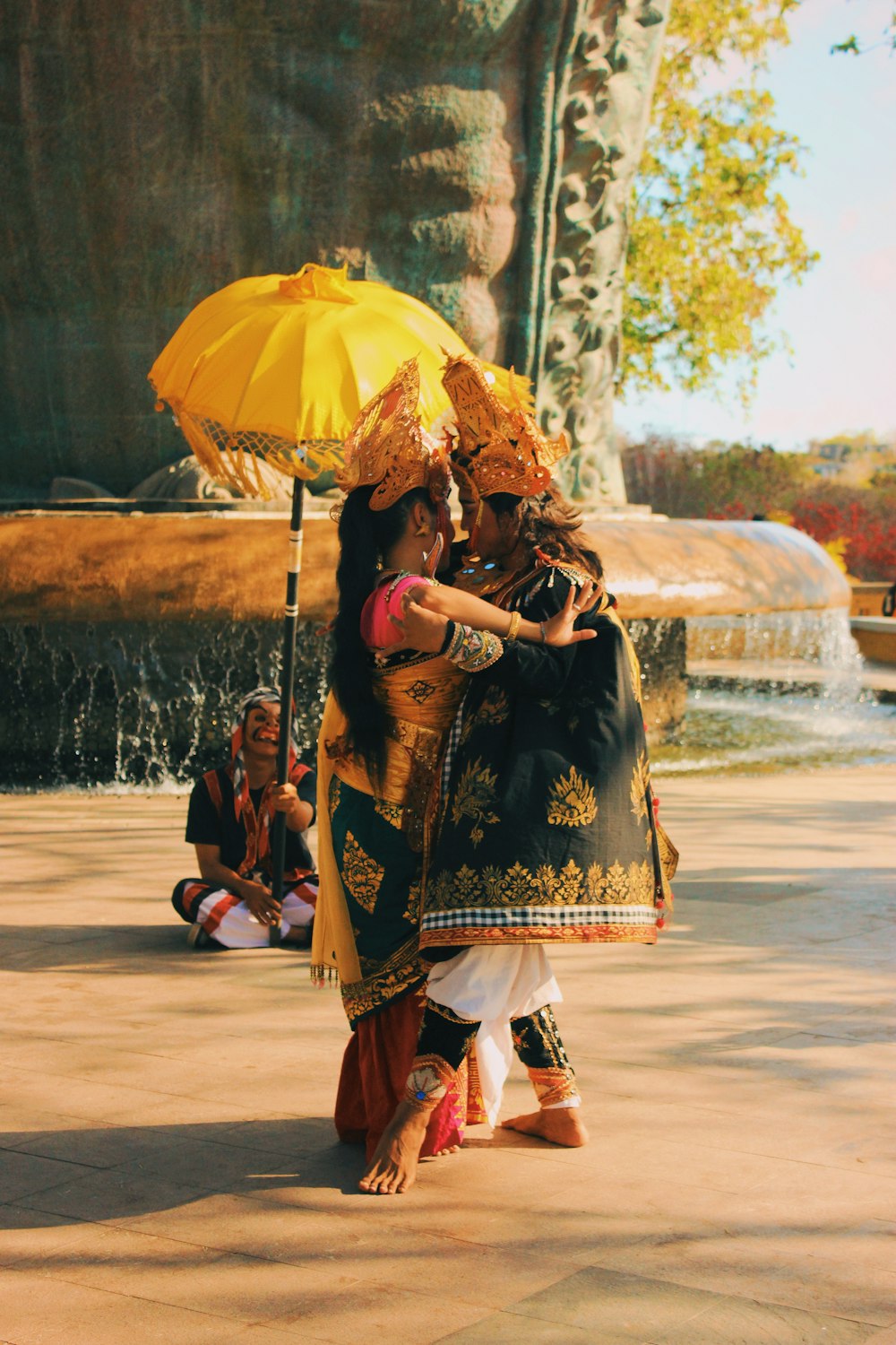 a couple of women standing next to each other under a yellow umbrella