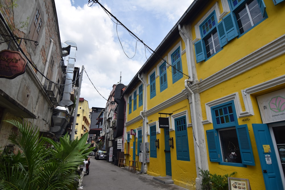 a yellow building with blue shutters on a street
