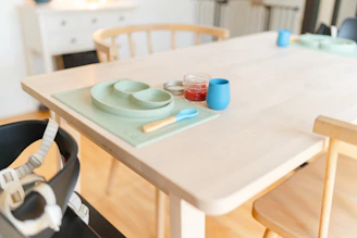 A colorful set of toddler feeding utensils arranged neatly on a wooden table.