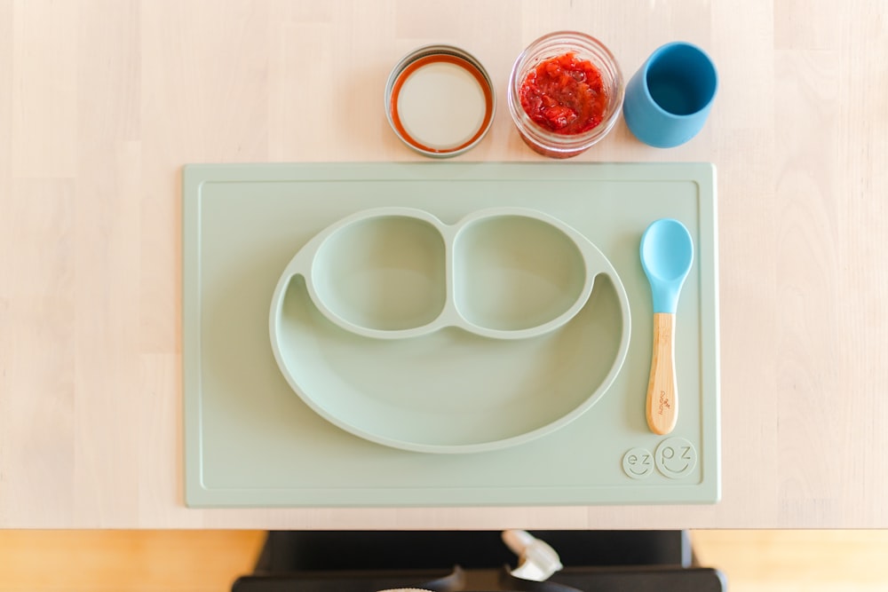 a child's plate with two spoons and a spoon rest on a stove