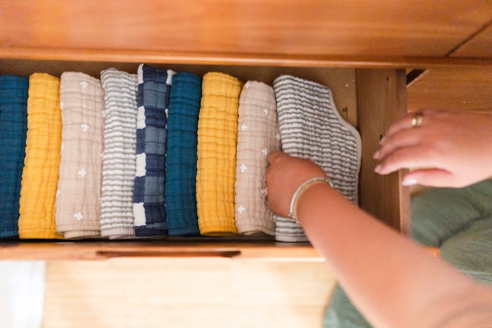 a woman is looking at a drawer full of sweaters
