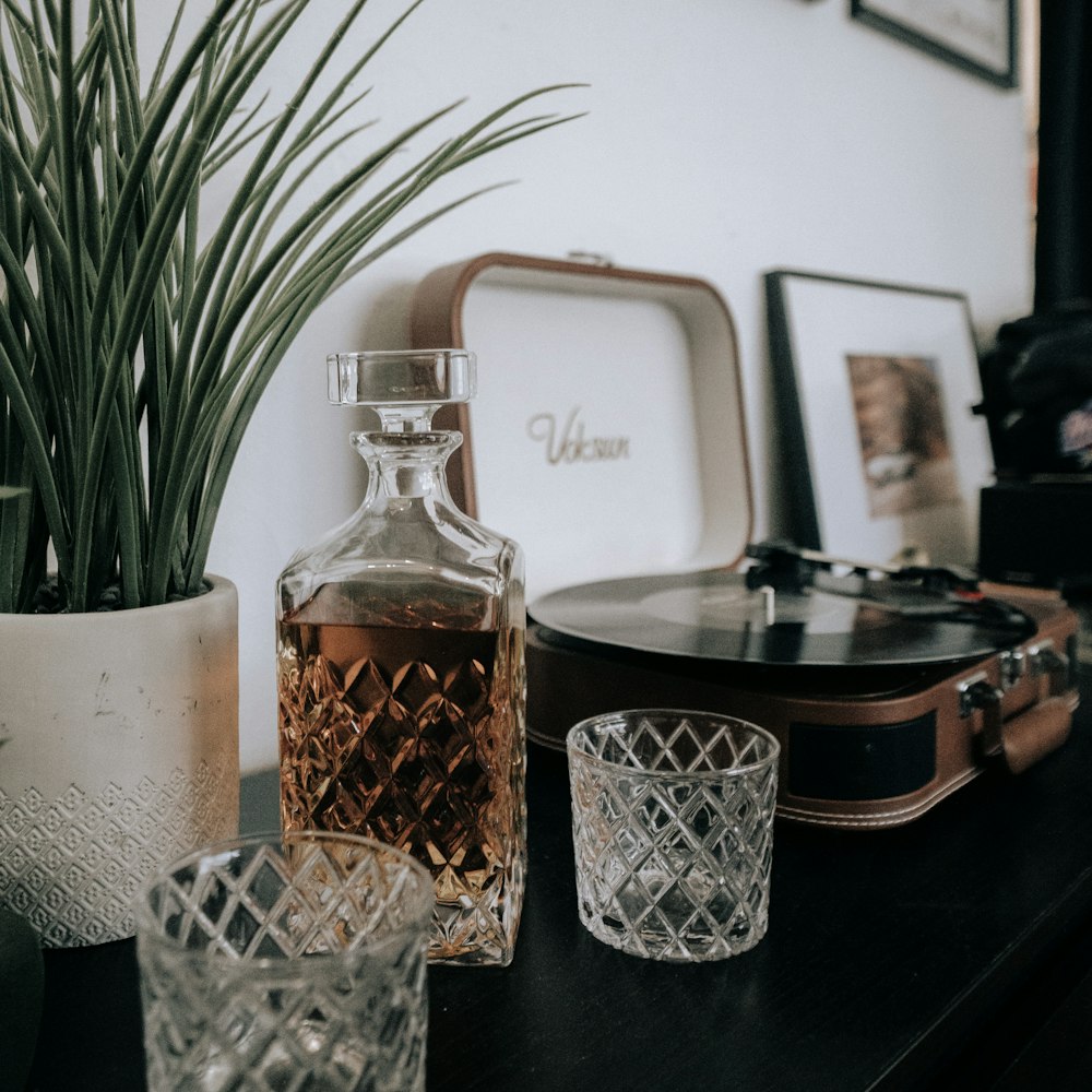 a bottle of whiskey sitting on a table next to two glasses and a record player