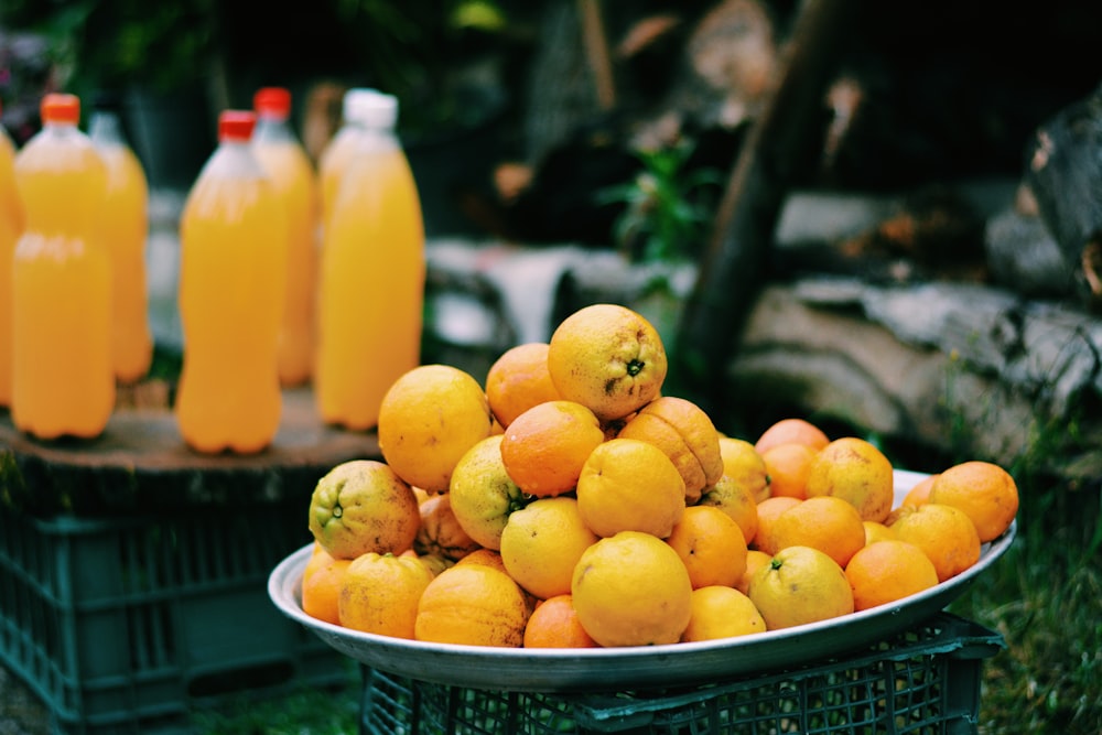 a bowl of oranges and bottles of orange juice