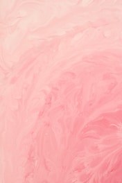 Swirling patterns of pastel pink and cream create a marbled effect, with soft textures and gentle curves throughout the composition.