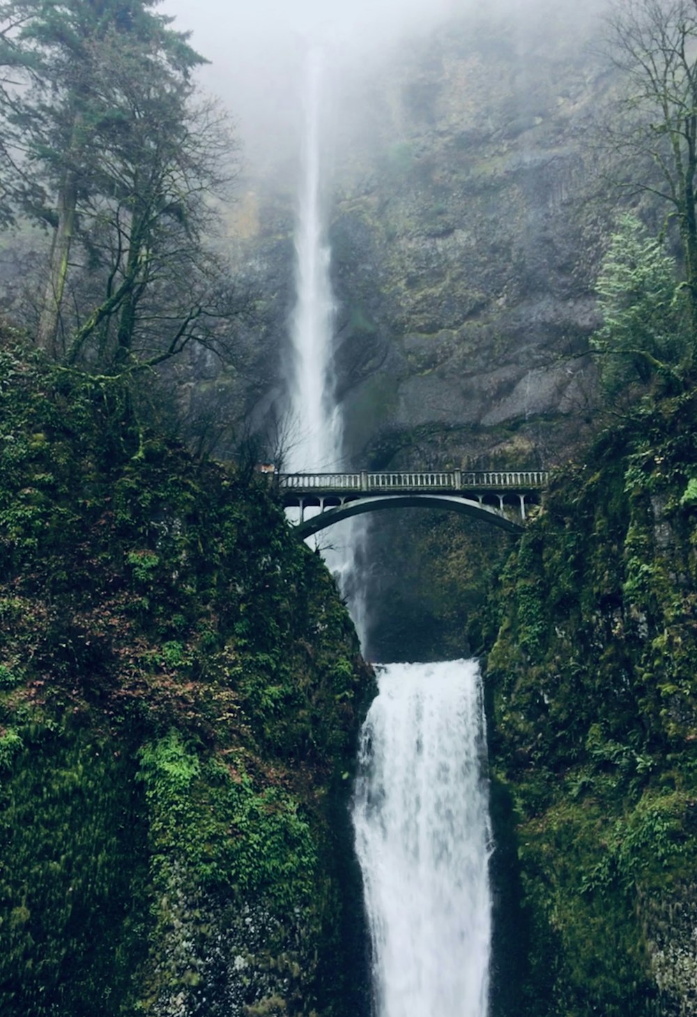 a large waterfall with a bridge over it