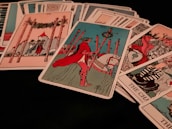 A collection of tarot cards is spread out, featuring various illustrated scenes and symbols. Dominant cards include a figure on horseback holding a staff, and another card shows a structure with four tall poles surrounding it.