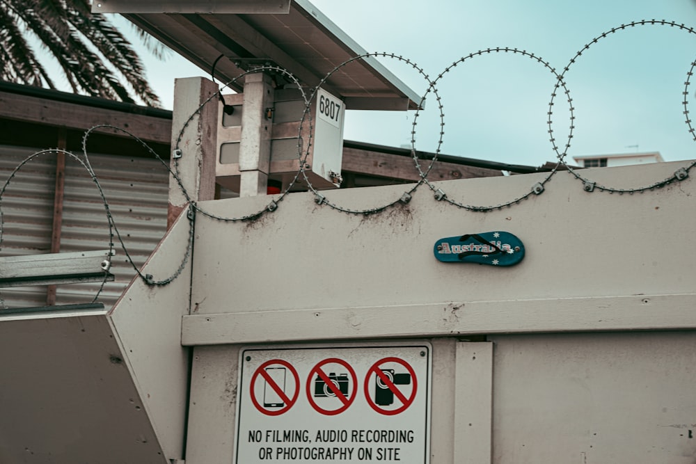 a sign on a building with barbed wire on top of it