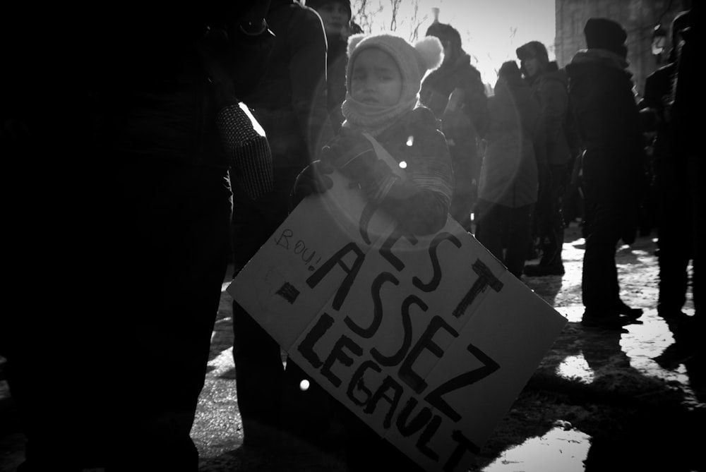 a little girl holding a sign that says assist