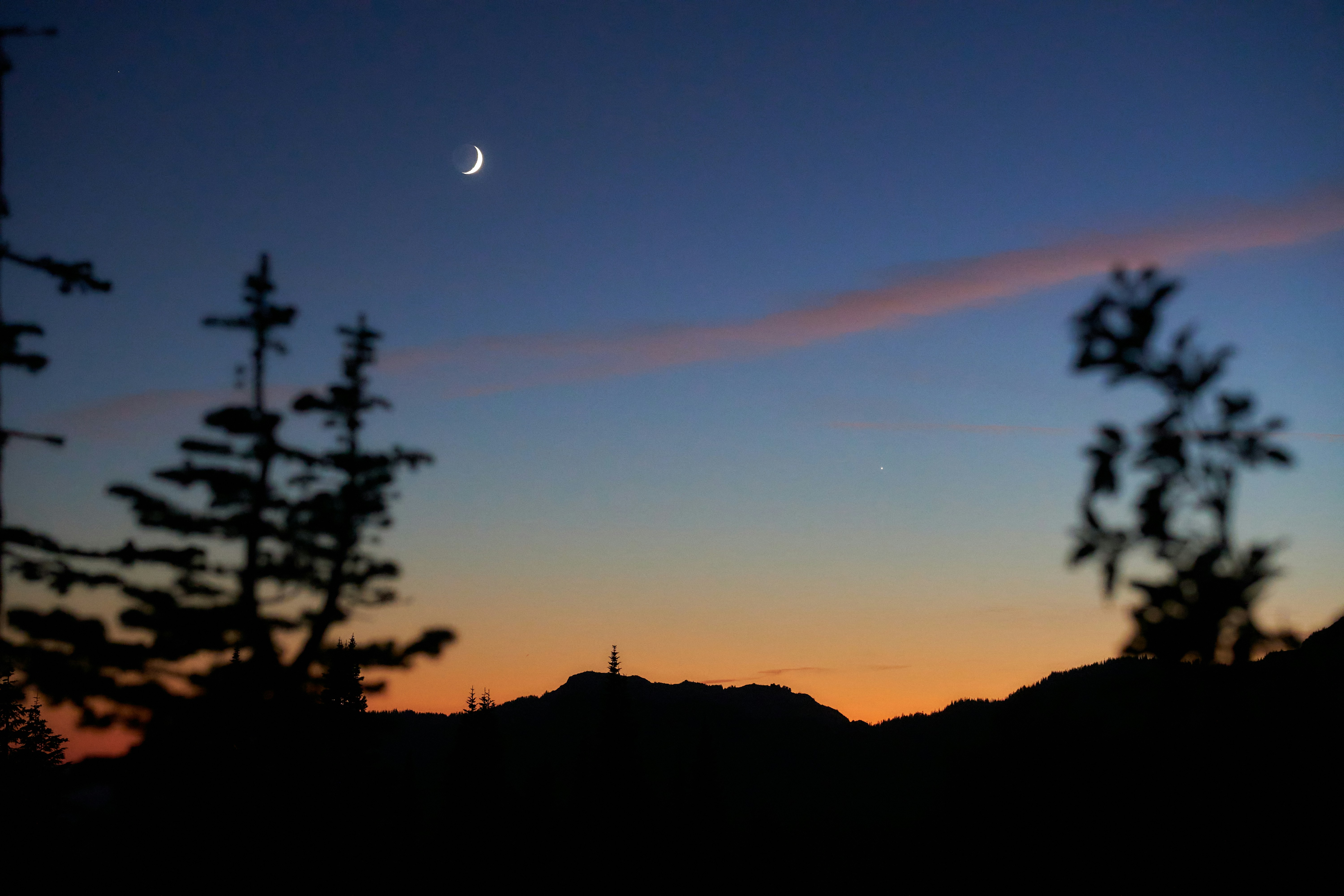 La luna sta tramontando sulle montagne e sugli alberi